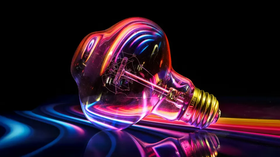 مصباح متوهّج بانعكاسات ملوّنة رمزاً للفكرة